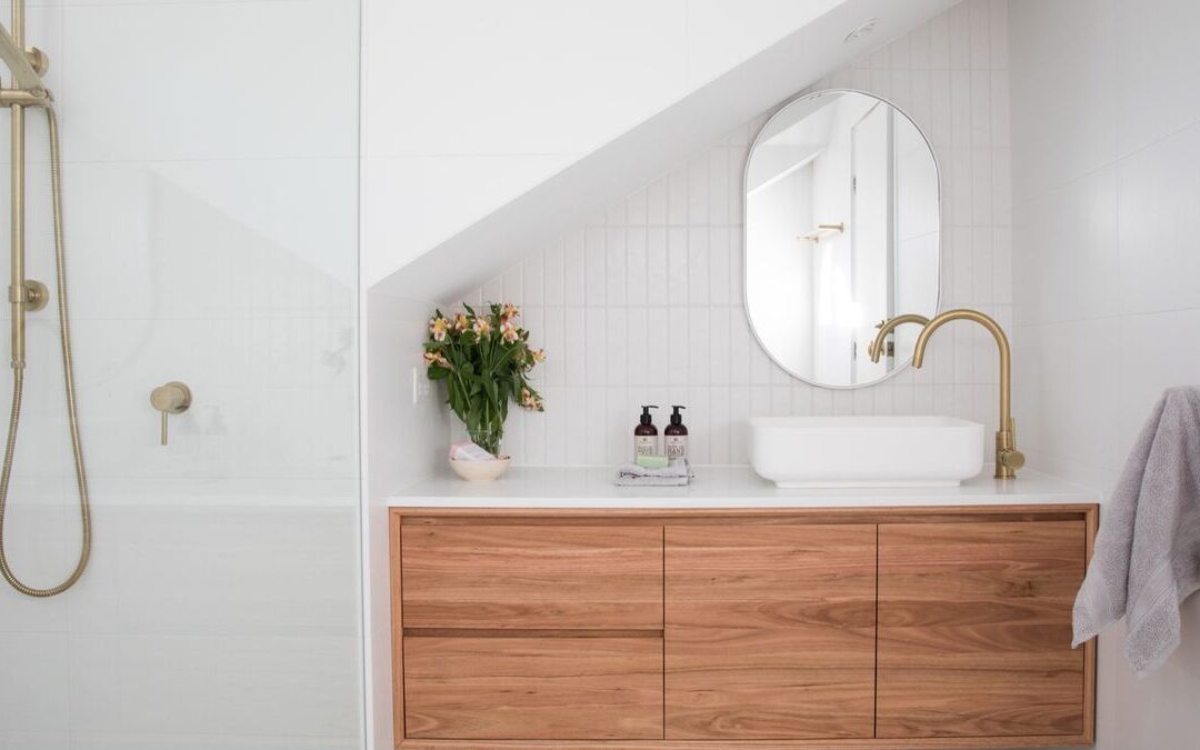 Compact bathroom with a floating wood vanity and round mirror, an approach often used in small bathroom remodeling